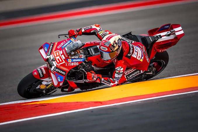 Jezdec MotoGP v náklonu s kolenem u asfaltu